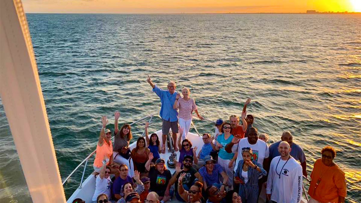 group of people posing for photo at edge of boat with view of water during sunset at Biscayne Bay Sunset Cruise in Miami, Florida, USA